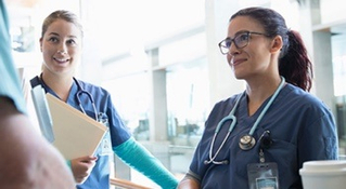 Smiling nurses consulting eachother