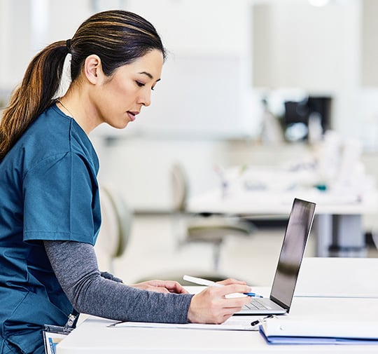 Three healthcare professionals in scrubs walking down a hallway