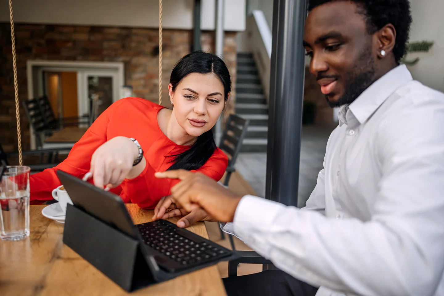 Portrayal of Capella business student talking to colleague pointing to a tablet screen.