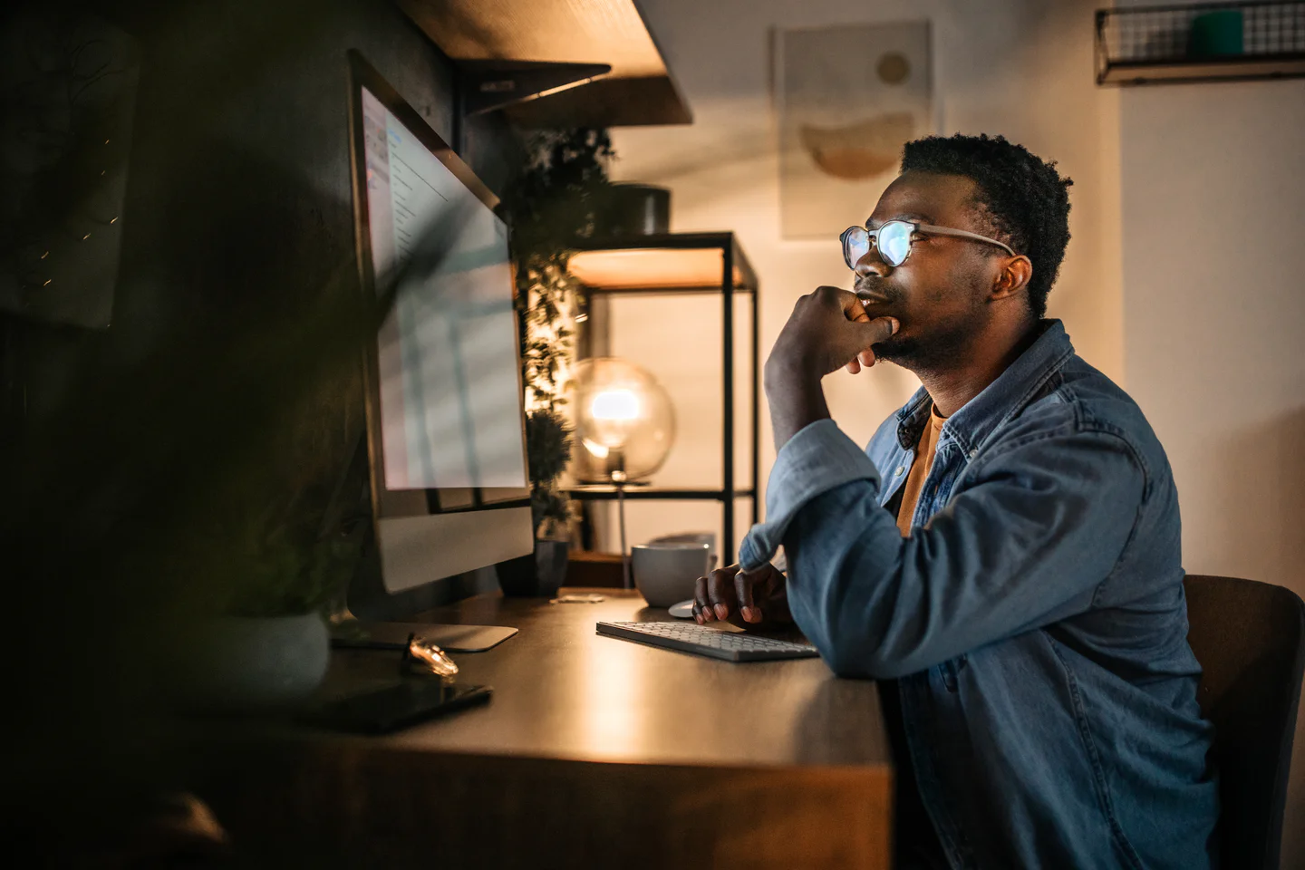 Portrayal of Capella online student working at a desktop computer in the evening.