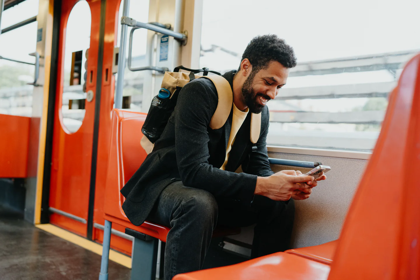 Portrayal of Capella University online student smiling at his cell phone while on public transit.