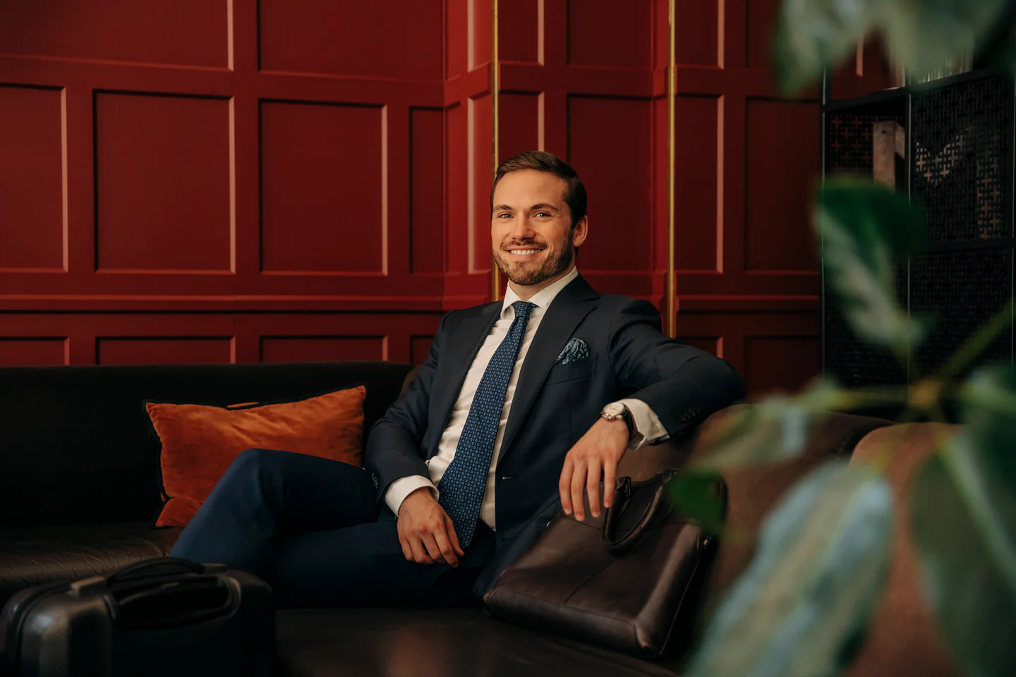 Portrayal of Capella business student in a suit and tie on a couch in an office.
