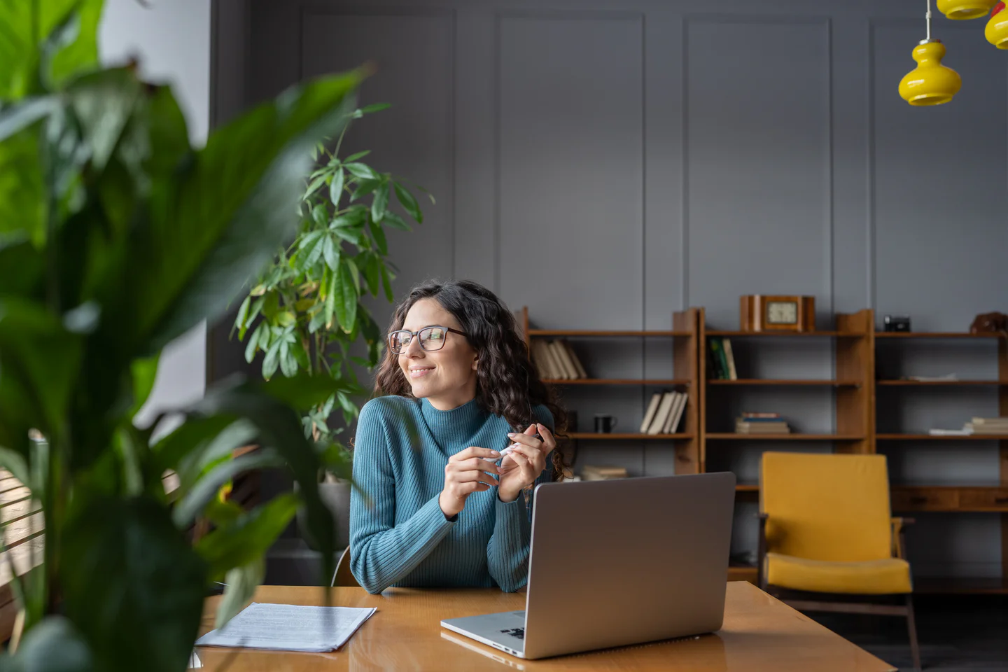Portrayal of a Capella University online student using her laptop at a&nbsp;table&nbsp;in a&nbsp;contemporary study space.