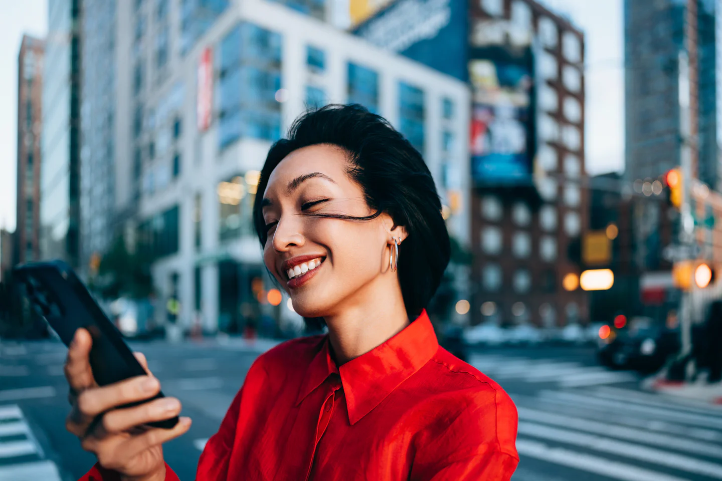 Portrayal of Capella student checking phone outside and smiling.