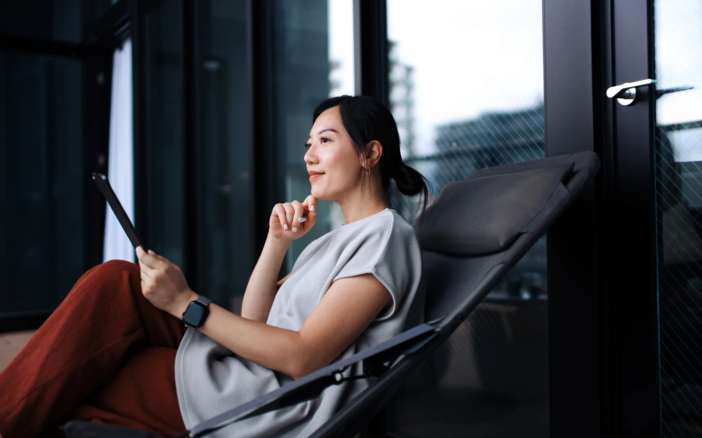 Portrayal of a Capella University online&nbsp;MS in School Counseling student sitting on a patio with a tablet.&nbsp;