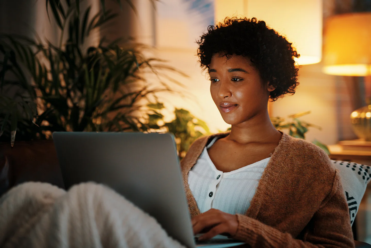 Portrayal of back lit Capella student in chair on her laptop.