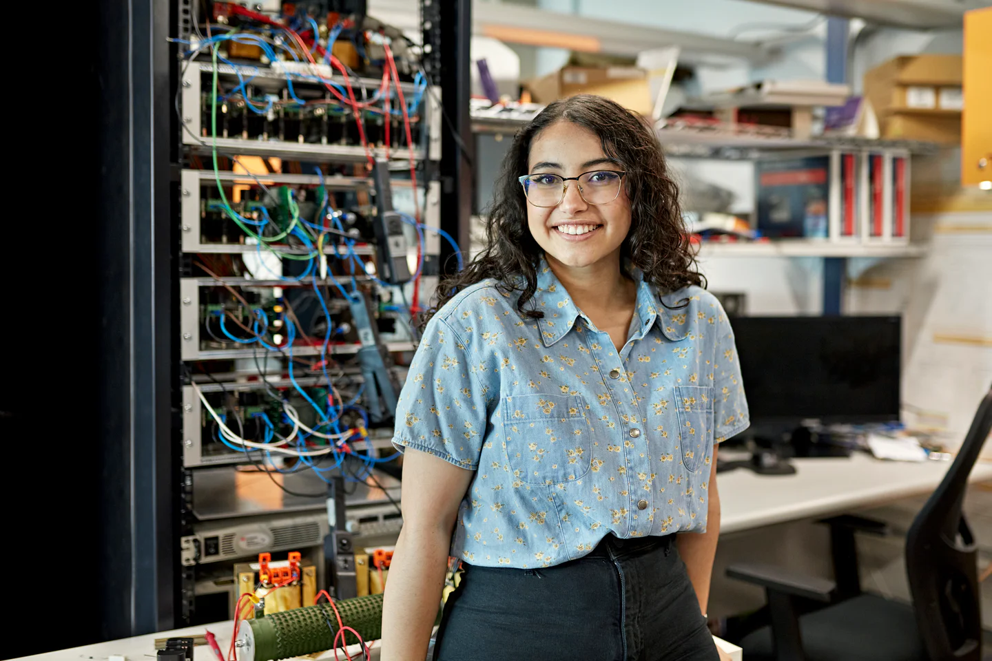 Portrayal of Capella IT student leaning on desk with computer circuitry behind her.