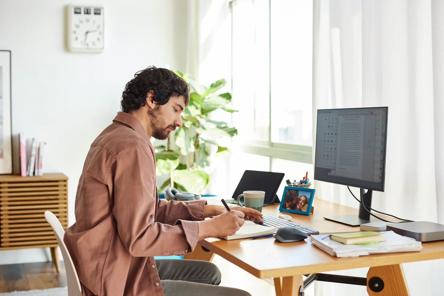Portrayal of Capella online student taking notes in his home office.