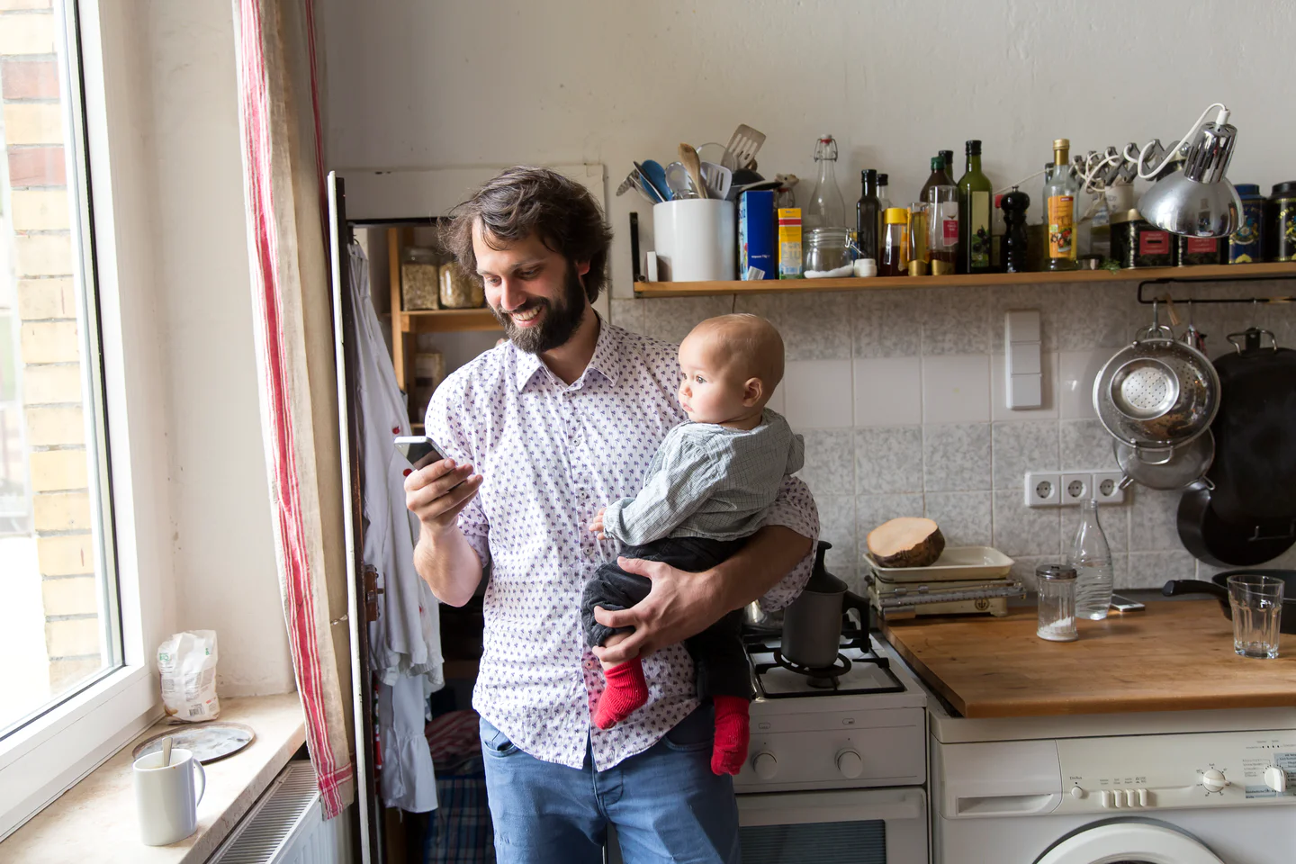 Portrayal of Capella University student on a laptop in her kitchen with family in the background.