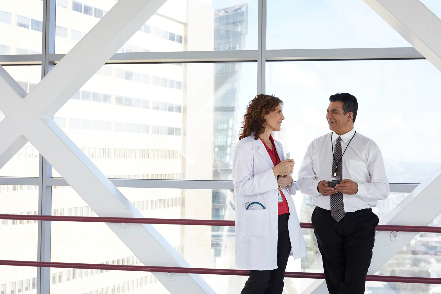 Portrayal of a Capella healthcare student talking with a colleague in a glass skyway.