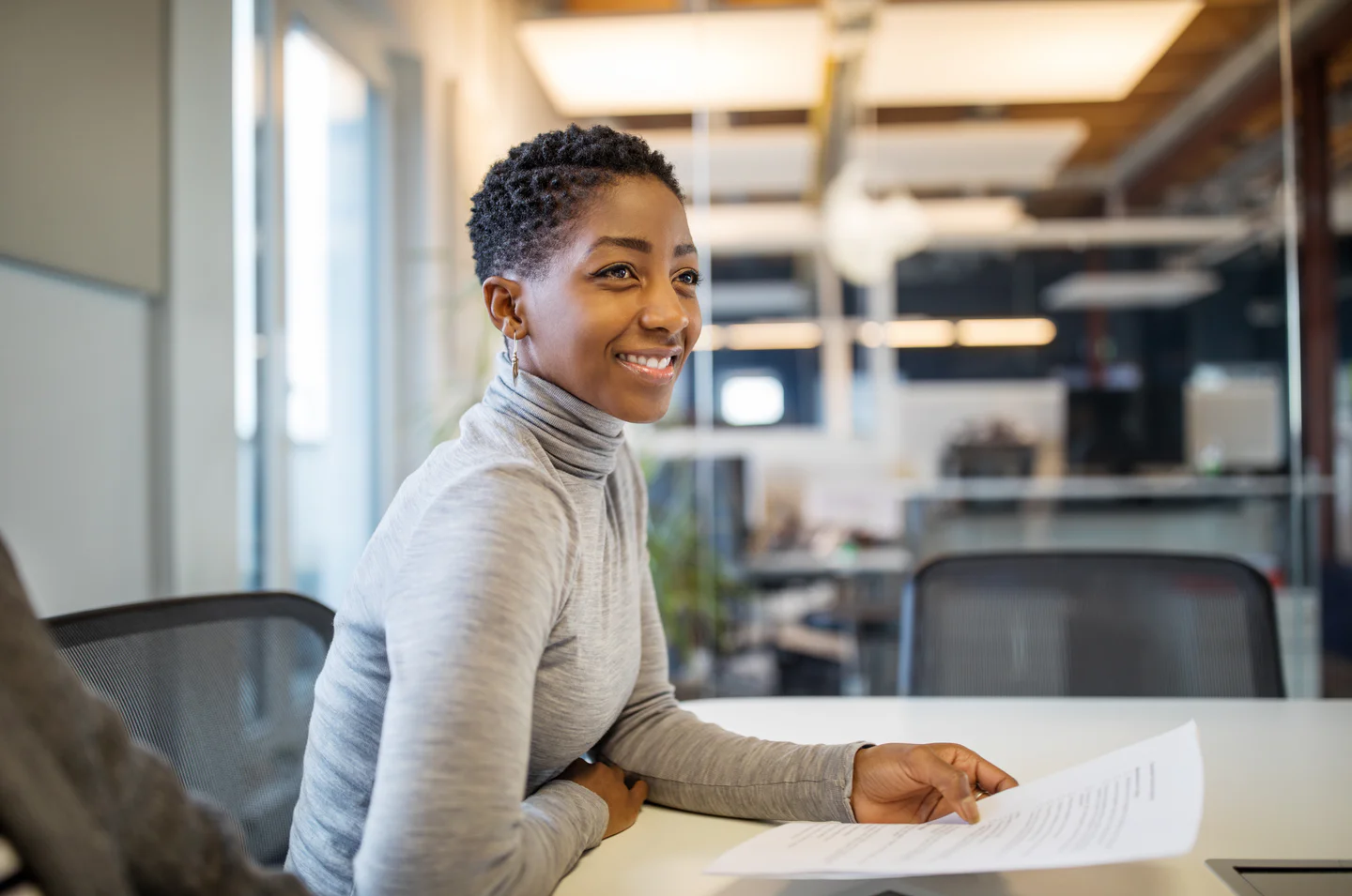 Portrayal of a Capella student sitting in an office holding papers.