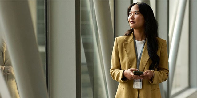 woman in beige blazer smiling in a hallway