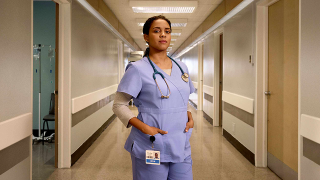 female nurse in scrubs standing confidently with a stethescope around her neck 