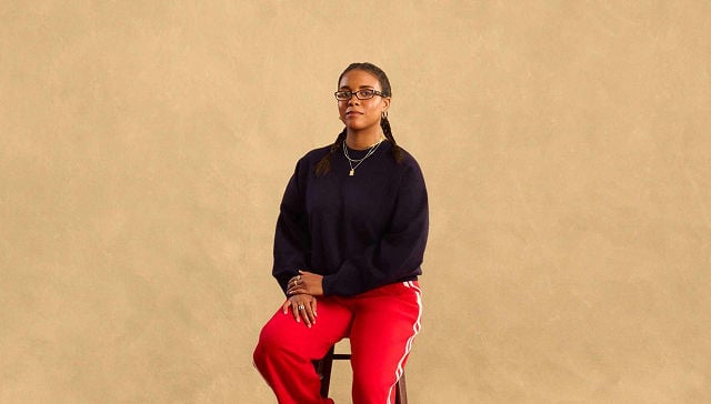 woman in black sweater and red pants sitting on a stool