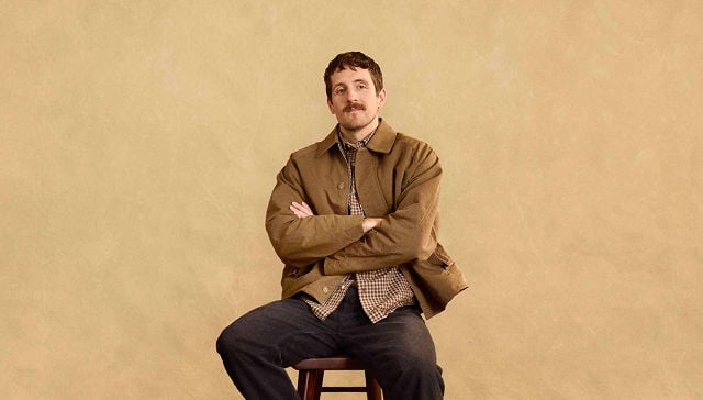 man sitting in beige blazer arms crossed