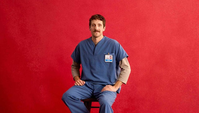 man in navy blue scrubs sitting on a stool