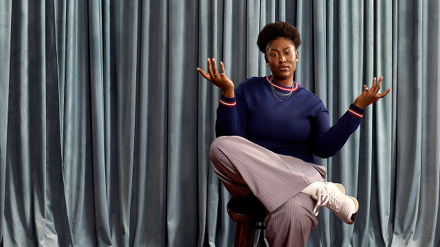 woman with hands up in the air with blue drapes behind her