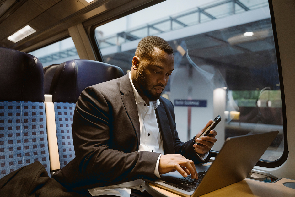 Portrayal of Capella University student on his cell phone and laptop while on public transit.
