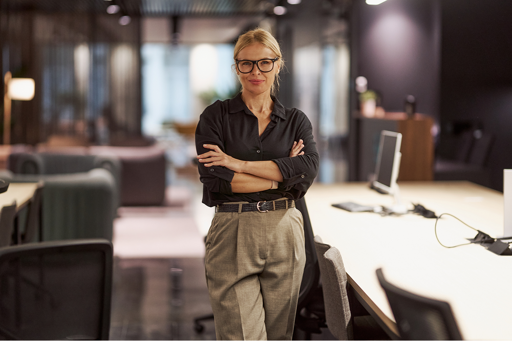 Portrayal of a Capella University online business student standing in a conference room.&nbsp;