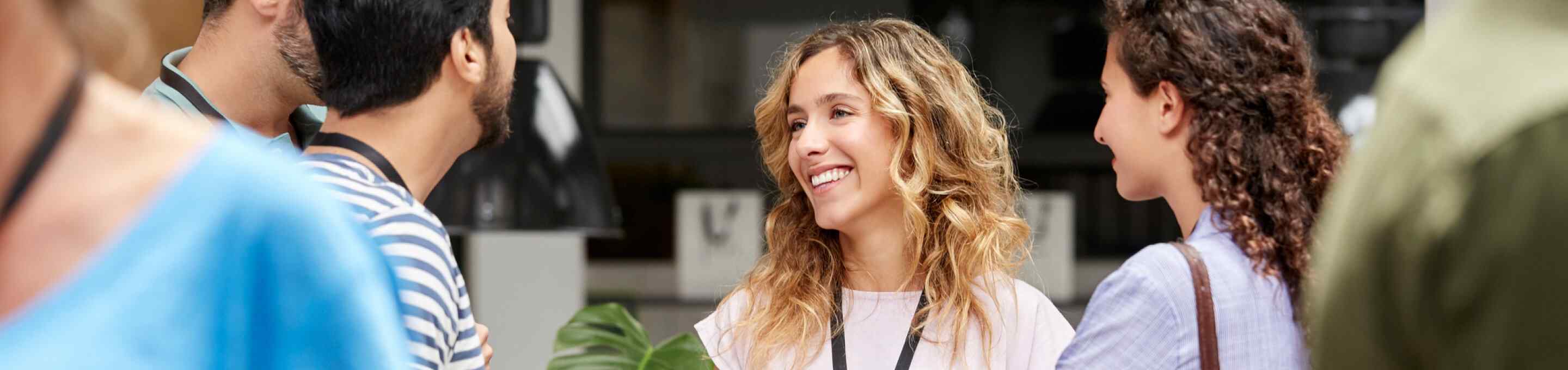 blonde women with lanyard talking to a group at a networking event