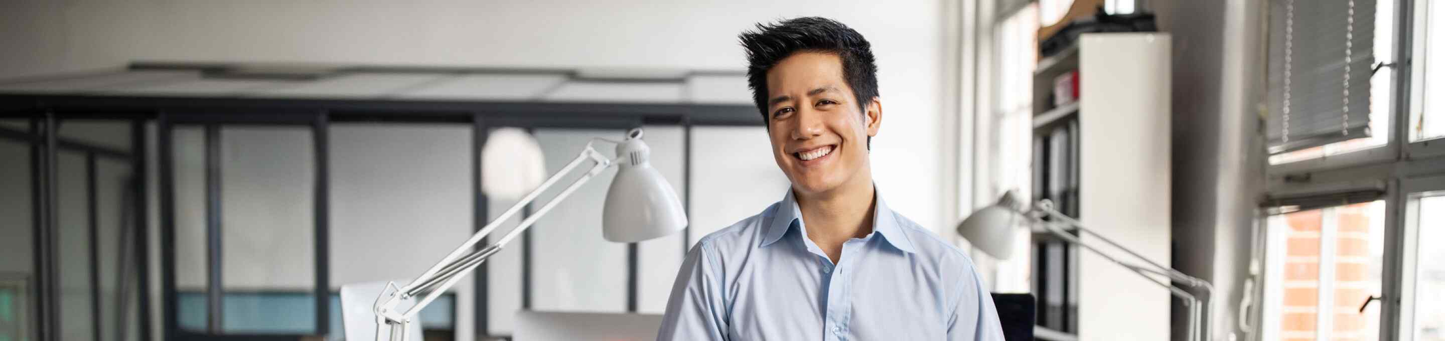 man in a light blue shirt smiling in an office
