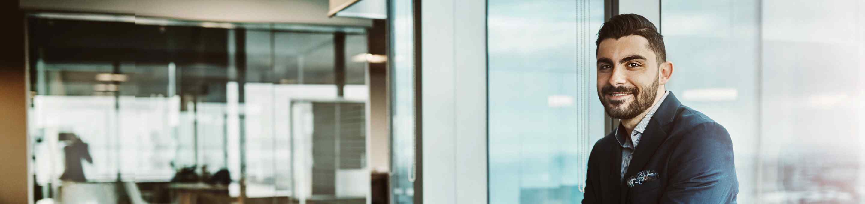 man in blue suit leaning in front of a glass window