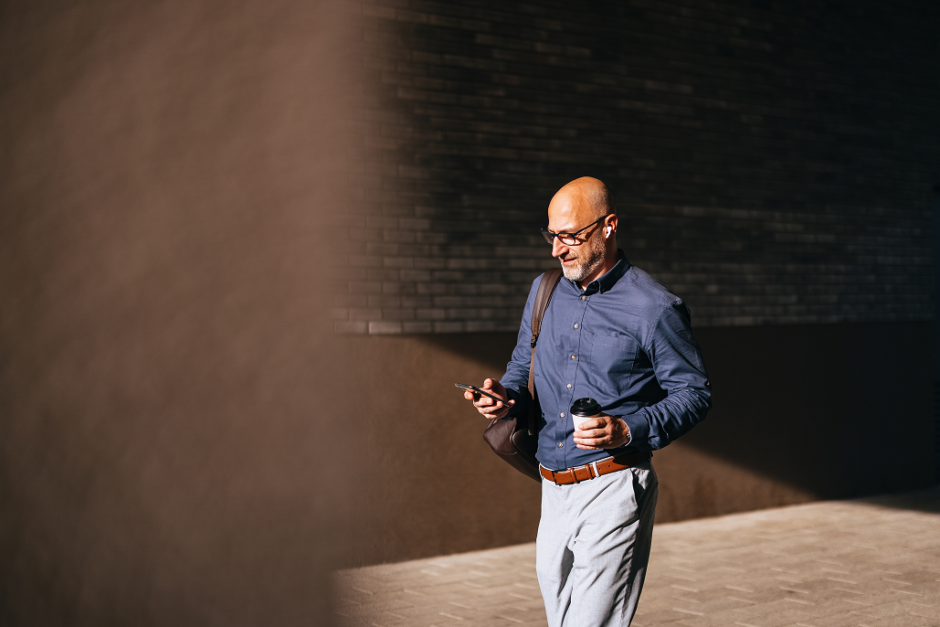 Portrayal of a Capella University online data analytics student walking and checking his phone.