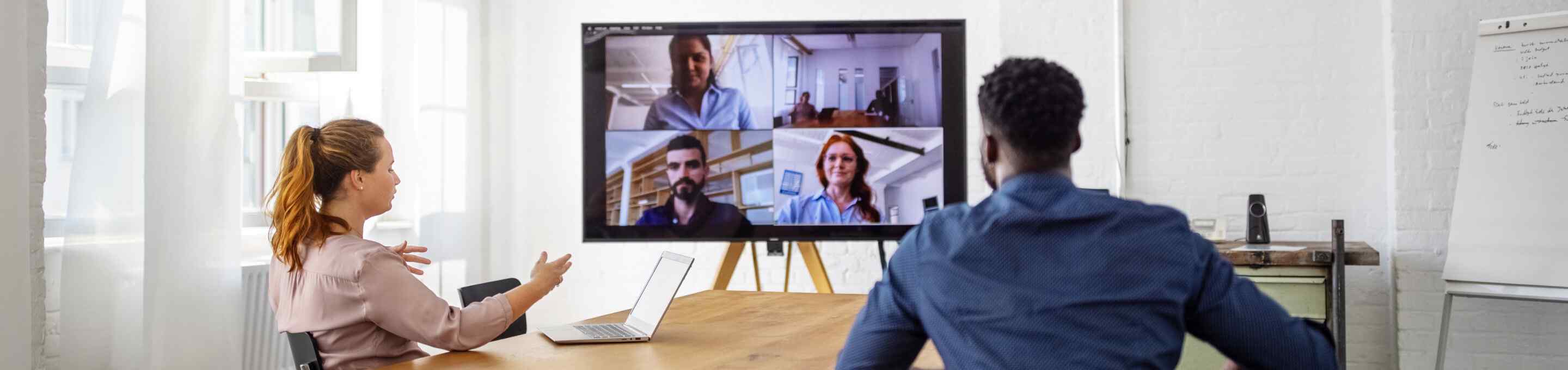 two people having a remote meeting on a large monitor