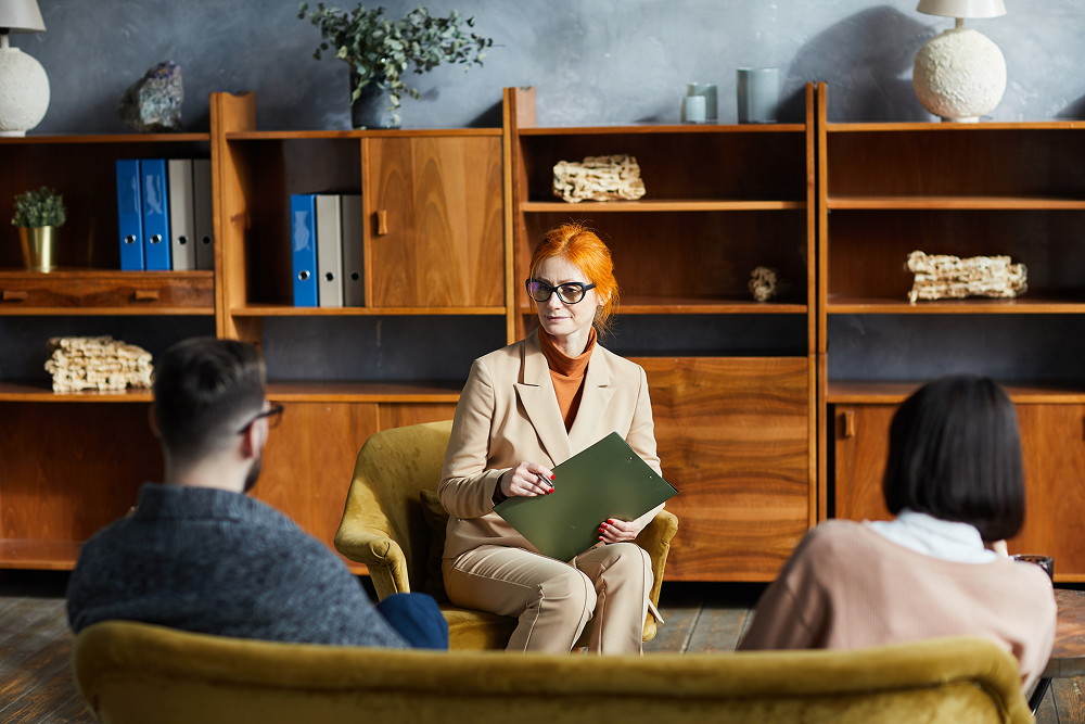 Portrayal of a Capella University student in a counseling and therapy setting speaking with patients.