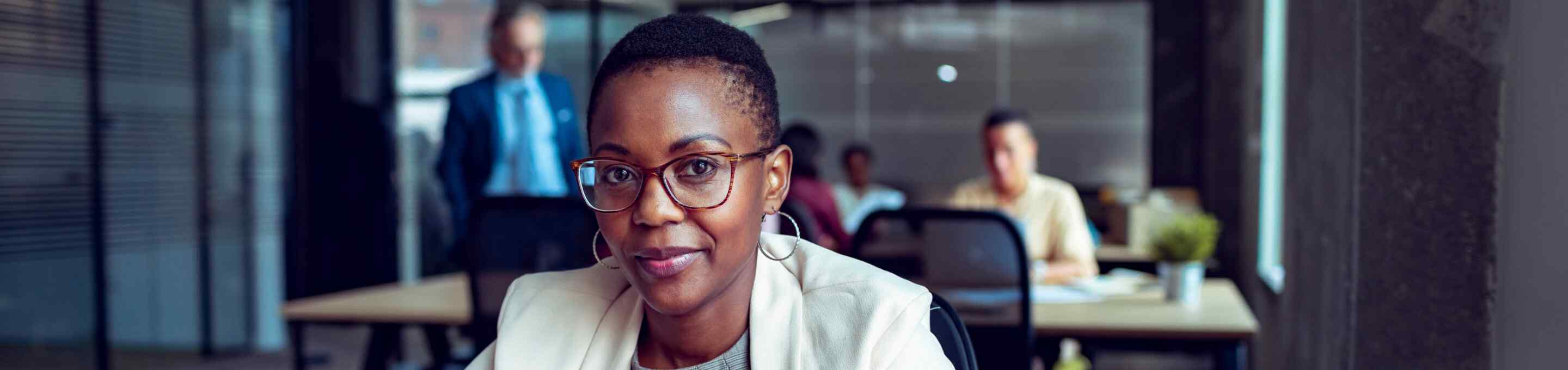 woman with hoop earing and beige blazer sitting confidently
