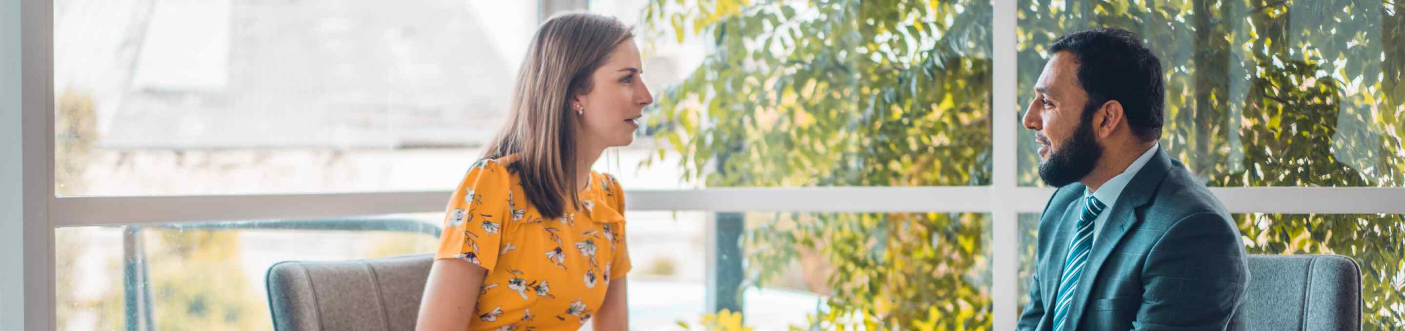 woman in yellow dress talking to a man in a grey suit