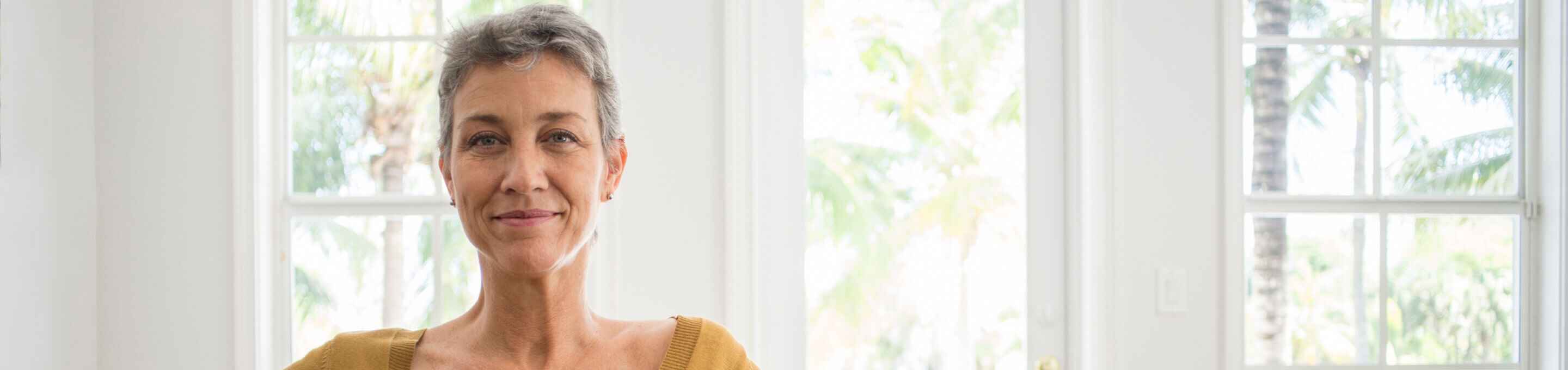 woman with grey hair and a yellow sweater smiling