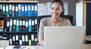 Woman in front of laptop smiling.