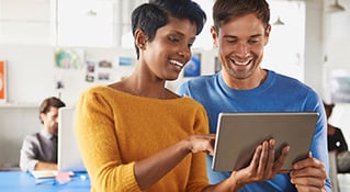 Smiling man and woman working on a tablet.