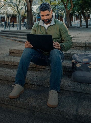Man sitting on bench with laptop