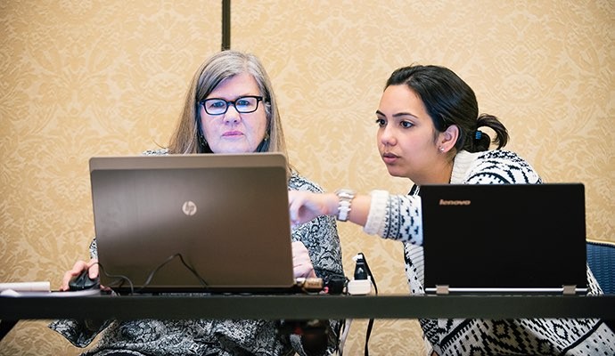 two women pointing at laptop