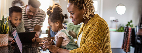 Family of 4 working around a laptop